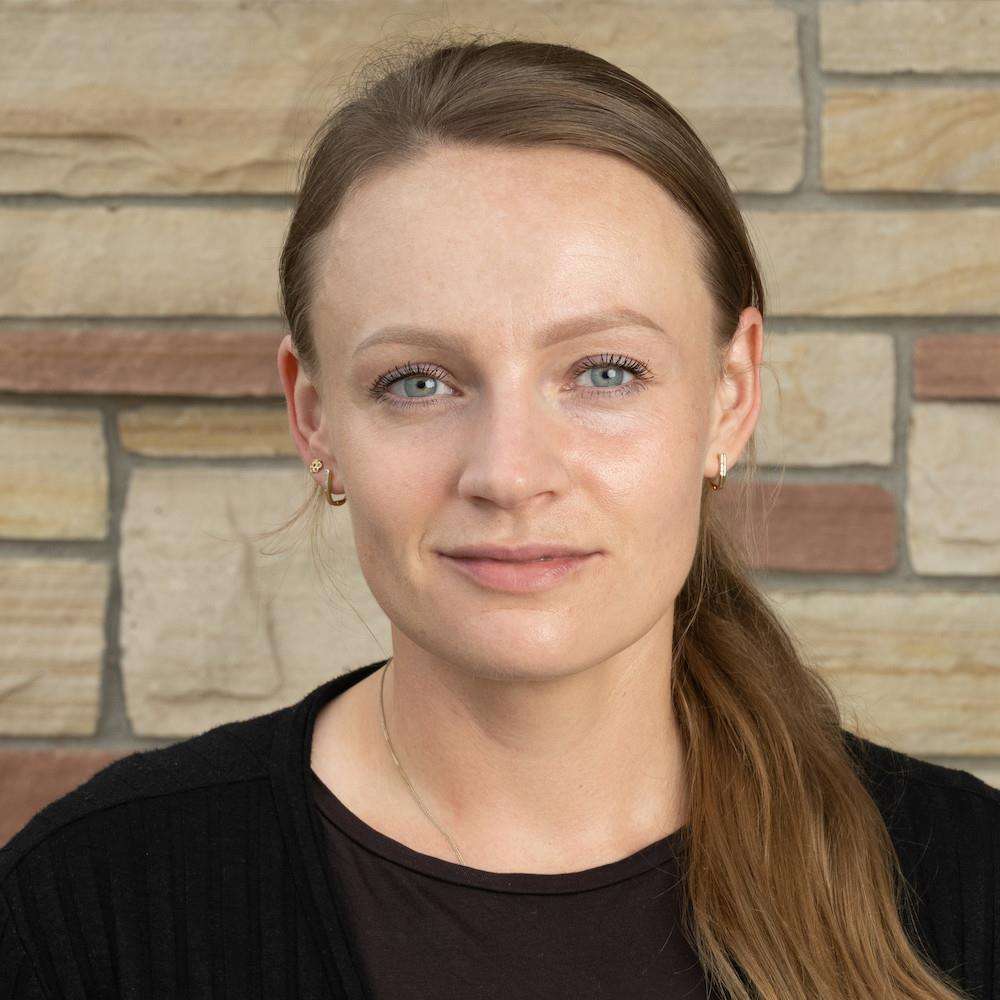 Headshot of Dr. Monika Samol in front of a brick wall from the shoulders up